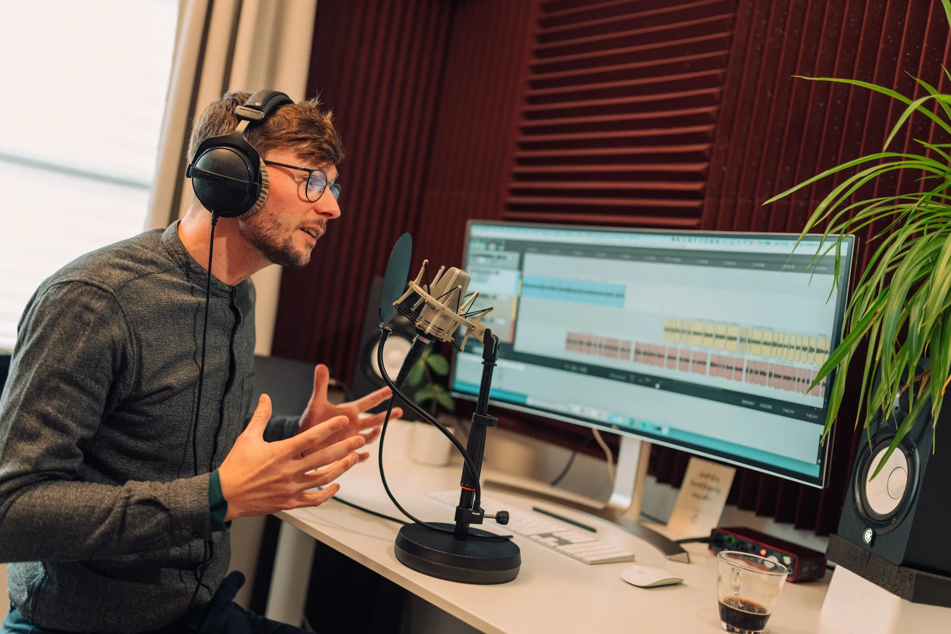 Stemacteur neemt op in zijn eigen studio, met koptelefoon en microfoon.