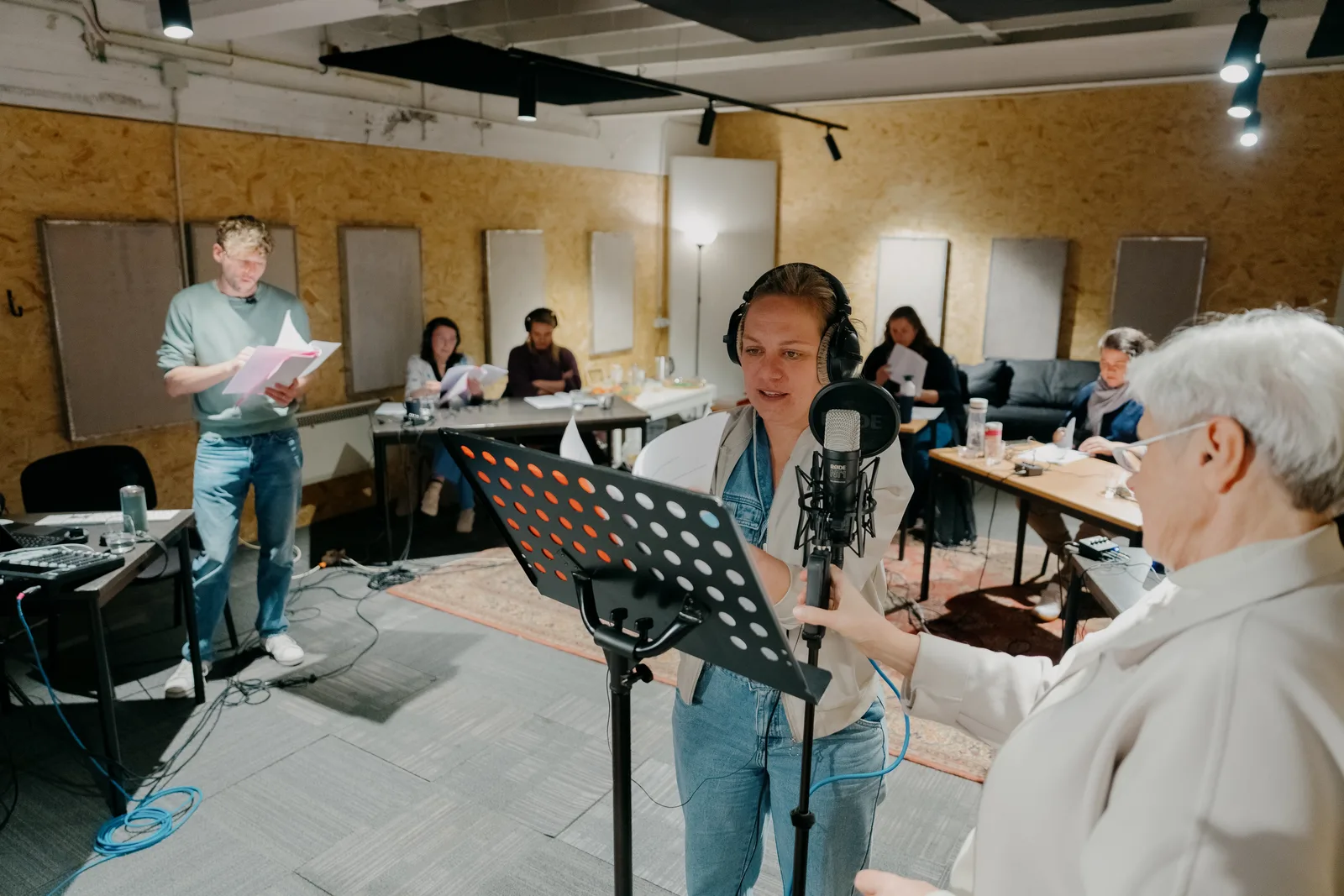 Stemacteur spreekt in aan de microfoon met koptelefoon in de Voices Studio.