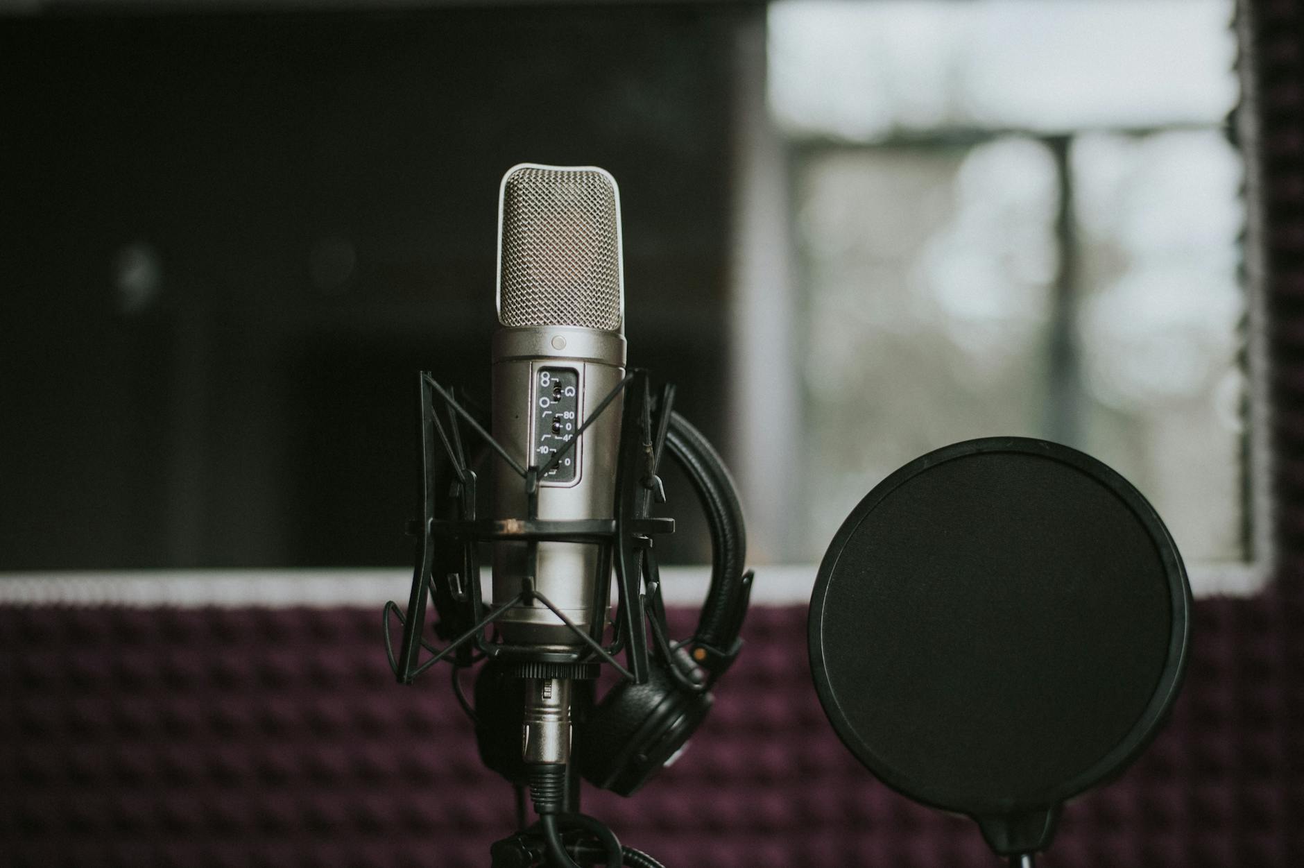 Close-up of a microphone with pop filter in a modern music studio environment.
