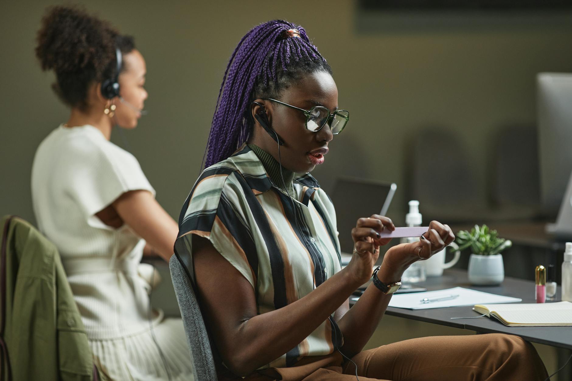 Two women multitasking in a modern call center office setting, displaying focus and professionalism.
